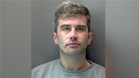 Kieran Roche: a police custody image of a man with short light-brown hair wearing a grey round-necked T-shirt