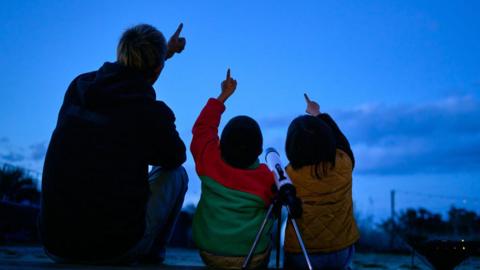 Father and children stargazing. 