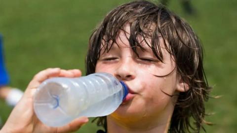 hot sweaty boy drinking water from a bottle