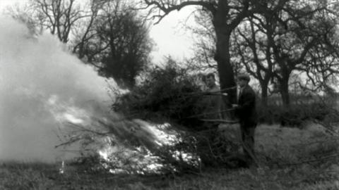 Two men build a bonfire