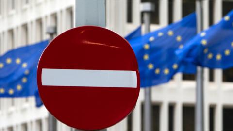 EU flags flutter in the wind in back of a no entry street sign in front of EU headquarters in Brussels on Friday, June 24, 2016.