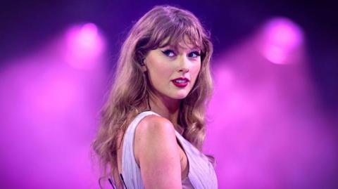 Image of Taylor Swift set against a purple backdrop.