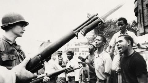 Y fyddin o flaen criw o ddynion