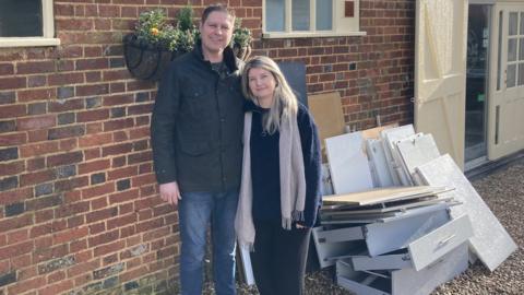 Roy and Sylwia Meek stood outside their cafe next to piles of kitchen worktops and drawers