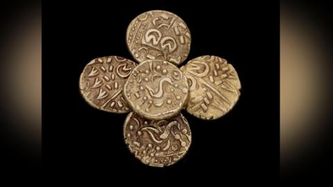 Four gold coins which date back from the Iron Age, with a black background