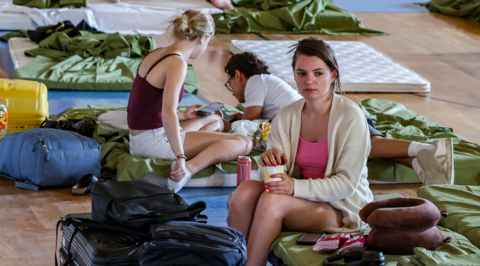 Women sit on mattresses after being evacuated from Crete