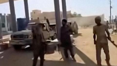 Armed men around a pick-up truck.