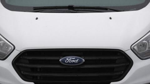 A frontal view of a white Ford Transit van