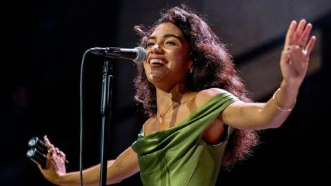 Olivia Dean stretches her arms out while she sings at Manchester's Albert Hall