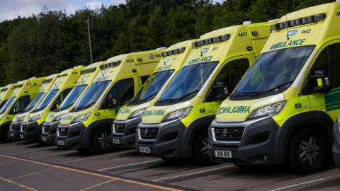 A long row of multiple ambulances parked up. 
