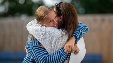 A student hugs her mother after receiving her GCSE results 
