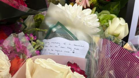A close-up of a collection of floral bouquets, which includes a handwritten note.