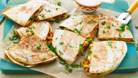 Quesadilla quarters sit on baking paper on a chopping board