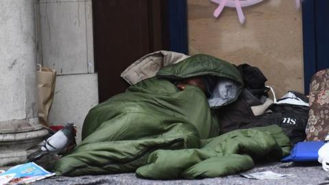 A homeless man sleeping in a doorway