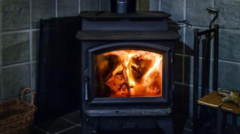 A domestic wood burner alight with the door open.
