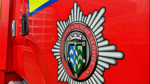 A Cumbria fire and rescue service logo pictured on the side of a red fire engine.
