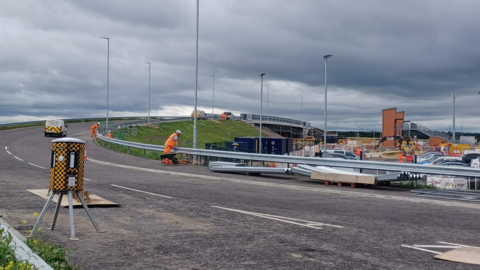 A road bridge curling away into the distance with work being done to the safety barriers 