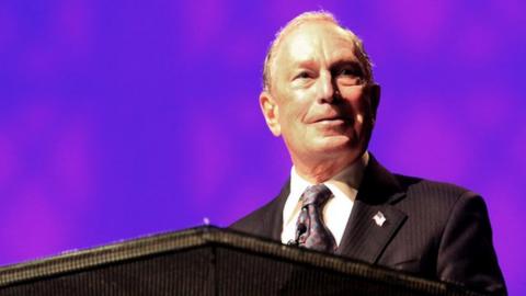 Michael Bloomberg speaking at a podium at the Christian Cultural Centre in Brooklyn