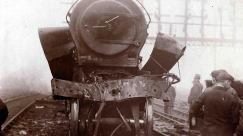 A black and white picture of one of the steam locomotives in the aftermath of the crash. Much of the metalwork at the front is mangled.