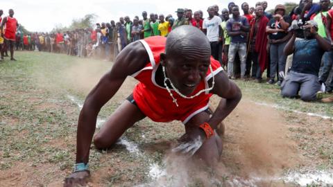 A Maasai Moran falls after throwing a javelin