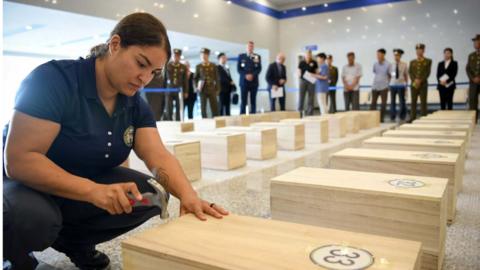 A US forensic anthropologist nails closed a box of remains thought to be of US soldiers killed in the Korean War