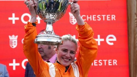 Saffie Osborne lifts the Chester Cup after victory on Metier