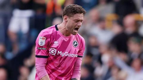 Millwall's Lukas Jensen, wearing a pink goalkeeper shirt, celebrates