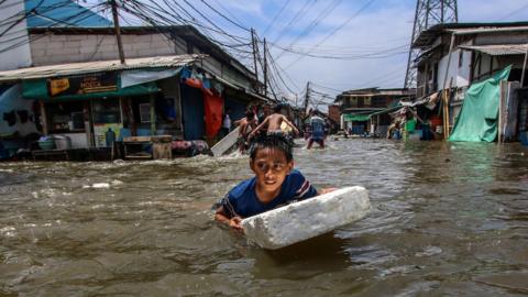 A boy struggling through a flooded street