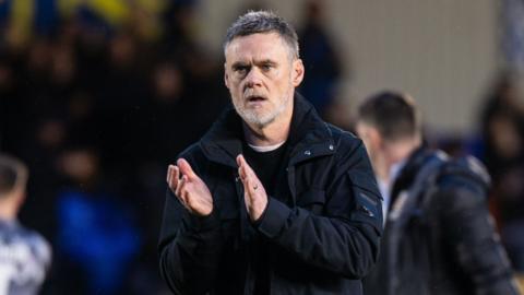 Bradford City manager Graham Alexander applauds the fans wearing waterproof jacket