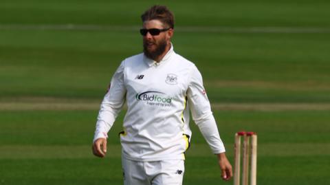 Chris Dent walks on the field during a County Championship match last season wearing sunglasses