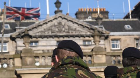 Armed Forces looking at a building with a Union Jack flag on