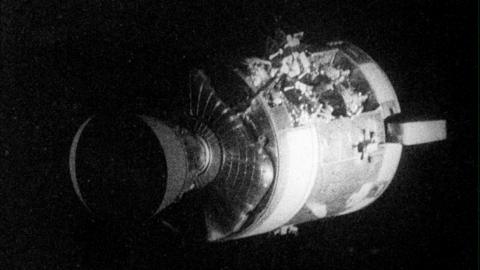 Apollo 13 service capsule is pictured with damage to its side.