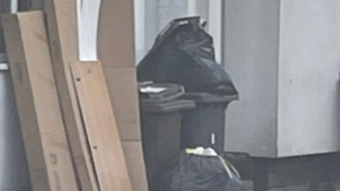 Cardboard, black bags and wheelie bins outside a house 