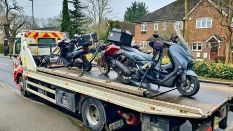 Three motorbikes on the back of a recovery lorry