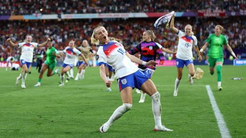 Chloe Kelly celebrates with her team mates running behind her after scoring the winning goal in the penalty shootout