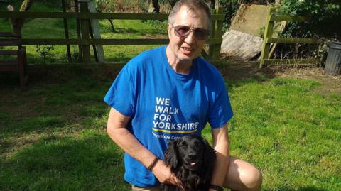 John Gaunt holding his dog, a black retriever