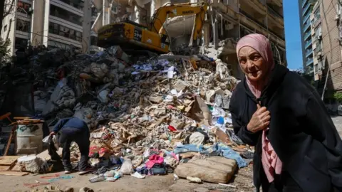 A woman walks next to a destroyed residential building the day after an Israeli airstrike in the Ain Mreisseh neighborhood of Beirut, Lebanon, 09 April 2026.
