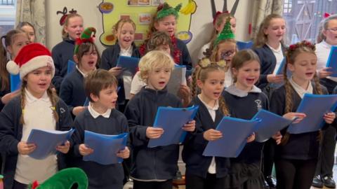 Kids singing in room with Xmas hats
