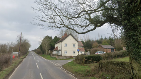 A country road, with a junction and house on the right hand side