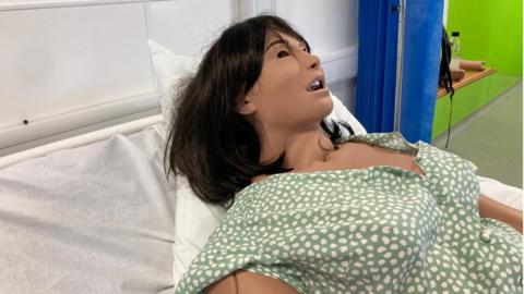 A mannequin is lying on a bed at the new care hub at New College in Swindon