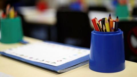 A pot of pens and pencils on a school desk