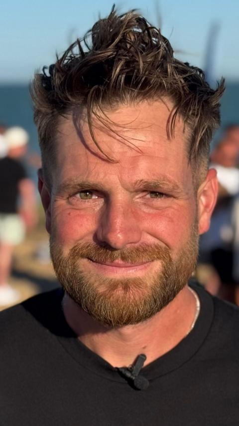 Close-up smiling man with brown hair and beard outdoors