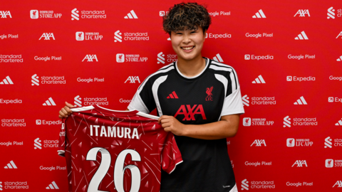Mao Itamura holds up a Liverpool shirt bearing her surname and the number 26 on the back