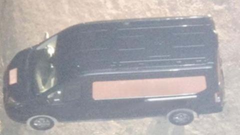 CCTV image of a close up of dark grey Transit van with a large orange panel on the side and a square of orange on the front bonnet