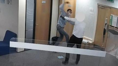 Cavan Medlock armed with a knife launches himself at a member of staff in the reception area of a law firm. There are doors in the background and a privacy screen in the foreground