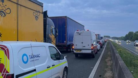 Lines of vehicles are standstill on the motorway, while the oncoming lane is moving.