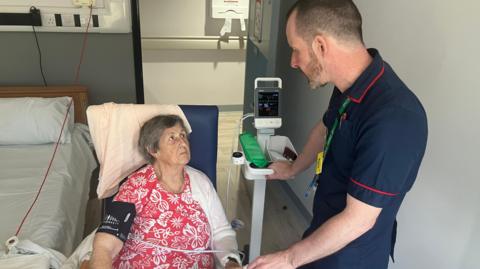 Doreen is sat in her newly-refurbished room at Preston Lodge having her blood pressure taken by the matron 