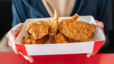 Person holding fried chicken in container