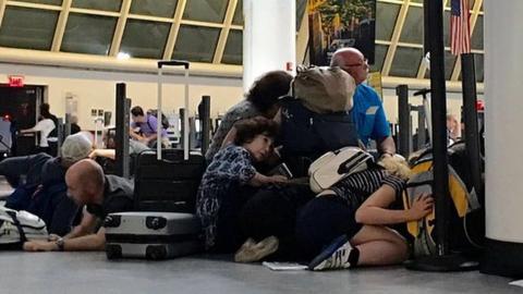 Passengers on the ground in the immigration area of JFK airport, 15 August