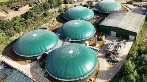 A bird's eye view of the site from September. All the tanks have been repaired. They have green roofs. It's sunny.